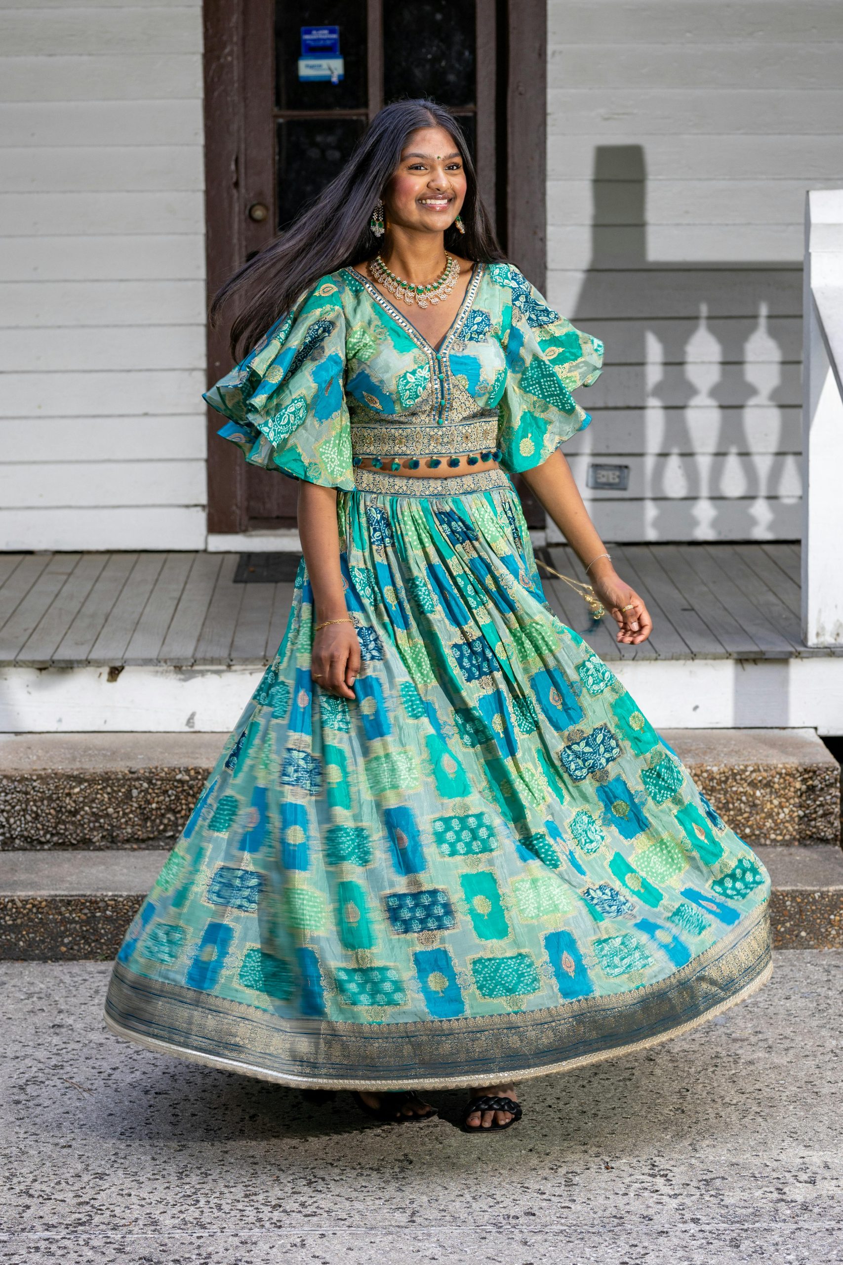 A woman twirls in a colorful traditional dress on a sunny day.